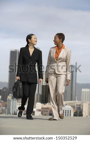 Full length of multiethnic businesswomen walking together in city