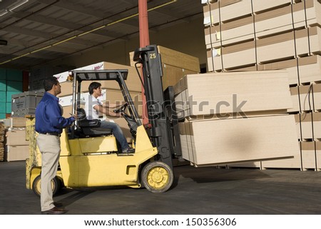 Warehouseman and forklift truck driver working in timber factory