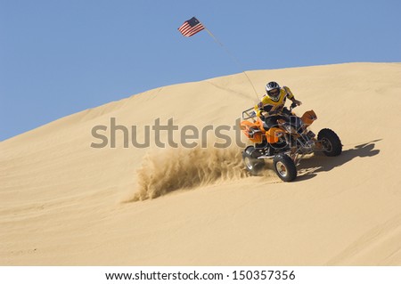 Young man riding quad bike in desert