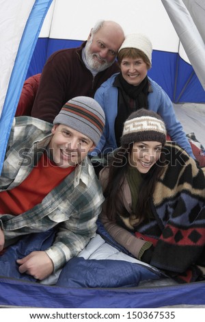 Portrait of happy family of four relaxing in tent while camping