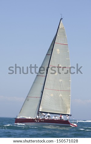 View of a yacht with white sail competing in team sailing event