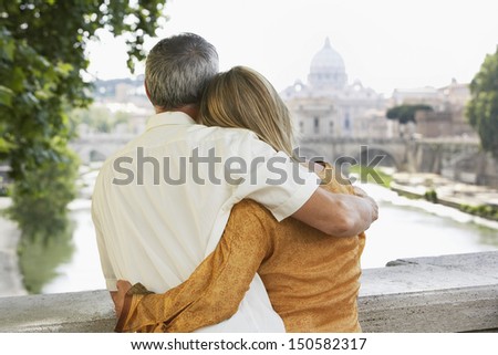 Rear view of middle aged couple on bridge looking at view of cathedral in Rome; Italy