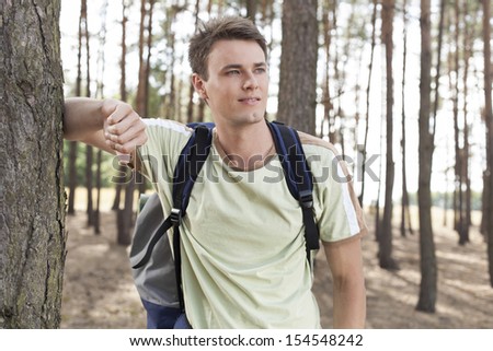 Happy young man with backpack hiking in woods