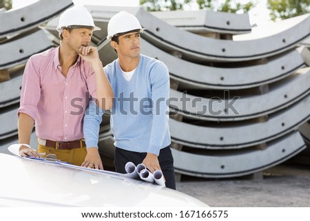 Architects with blueprints on car working at construction site