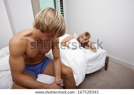 Sad man and woman on bed in house