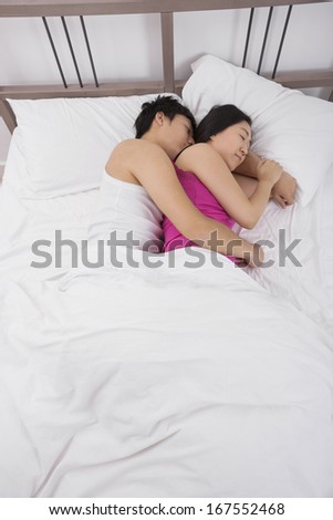 Asian couple sleeping arm around in bed