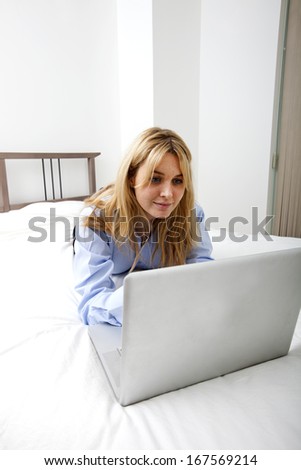 Businesswoman using laptop while lying in bed