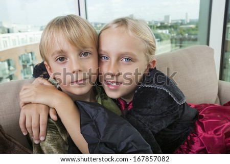 Portrait of cute siblings in dinosaur and vampire costumes at home
