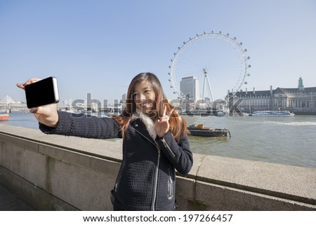 Happy woman taking self portrait through cell phone ; England; UK
