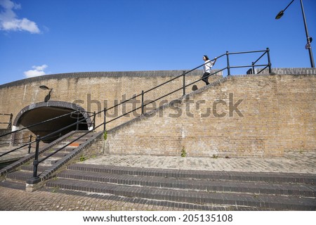 Side view of young woman walking down stairs against blue sky