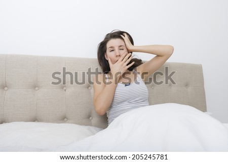 Sleepy woman yawning in bed