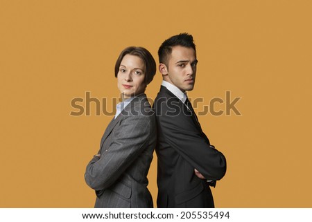 Portrait of a business partners standing back to back with arms crossed