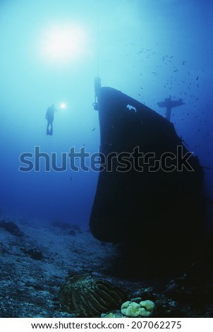 Underwater shoot of female scuba diver exploring sunken ship
