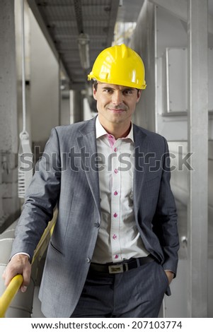 Portrait of confident young manager wearing hard hat in industry