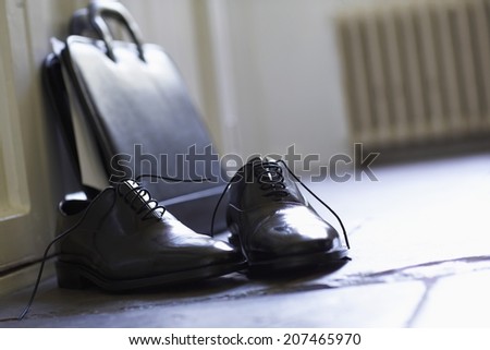 Closeup of formal shoes and briefcase on floor