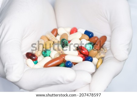 Closeup of pharmacist holding handful of colorful pills