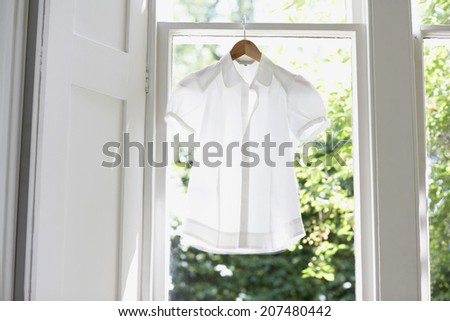 Blouse on hanger at domestic window