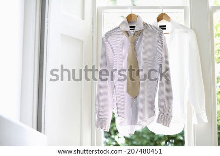 Two dress shirts on hangers at domestic window