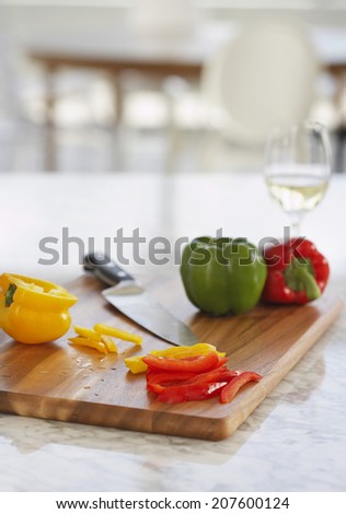 Peppers and knife on chopping board in kitchen