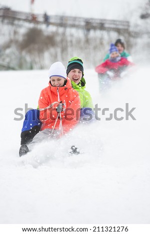 Young couple enjoying sled ride on snow covered slope