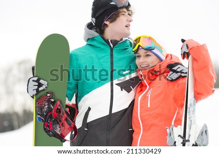 Young couple with snowboard and skis in snow