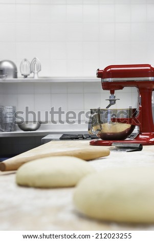 Closeup of dough on wooden board beside dough mixer in kitchen