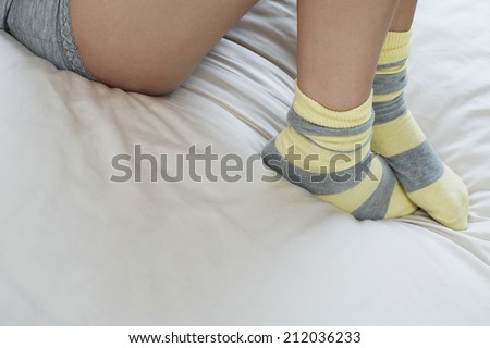 Low section of woman wearing socks lying in bed
