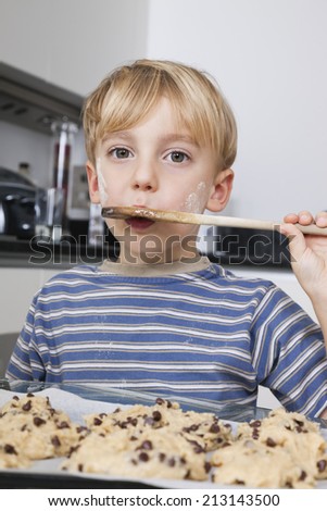 Portrait of young boy tasting spatula mix with cookie batter