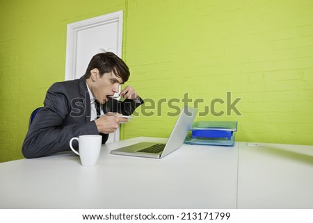 Side view of young businessman eating while using laptop at table