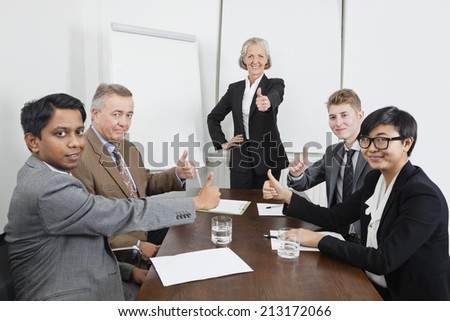Multiethnic business people giving thumbs up in meeting