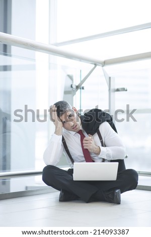 Stressed out businessman seated on floor working at laptop