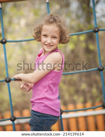 Young girl on climbing net turning to face camera