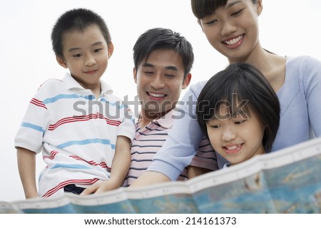 Family including boy and girl (7-9) reading map outdoors