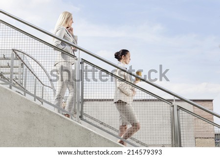 Profile shot of businesswomen moving down stairs together against sky