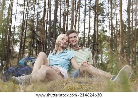 Full length of romantic young hiking couple relaxing in forest