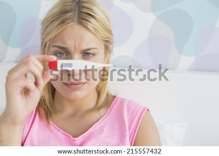 Close-up of sick woman taking temperature with thermometer in bed