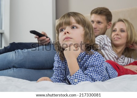 Family watching TV in bedroom