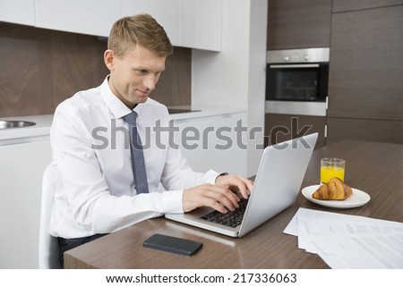 Businessman using laptop at breakfast table