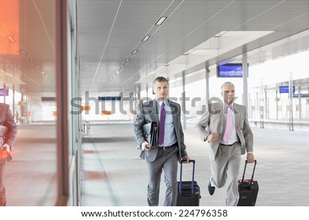Middle aged businessmen with luggage rushing on railroad platform