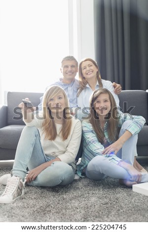 Happy family of four watching TV together at home