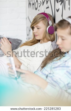 Sisters listening music through headphones at home