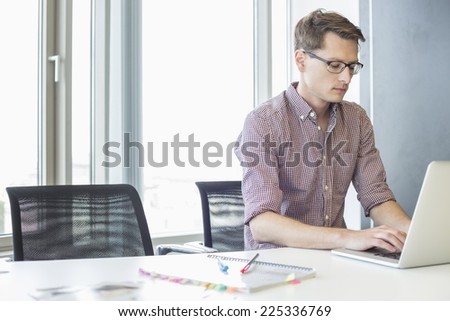 Businessman using laptop at desk in creative office