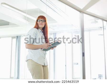 Creative businesswoman looking away while holding files in office