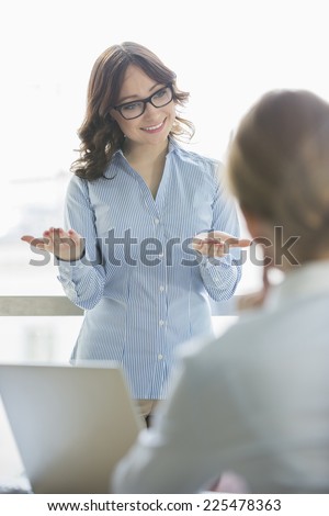 Happy businesswoman talking to businesswoman in office