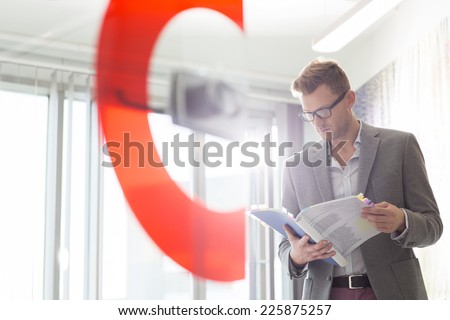 Mid-adult businessman reading file in creative office