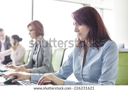 Businesswoman with colleagues working in open plan office