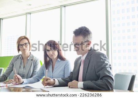 Business people writing on books at conference table