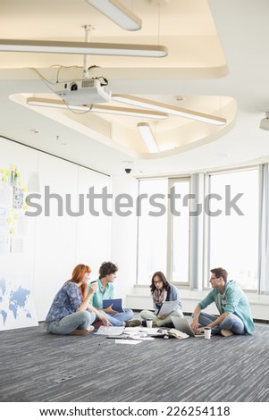 Businesspeople discussing while sitting on floor in creative office