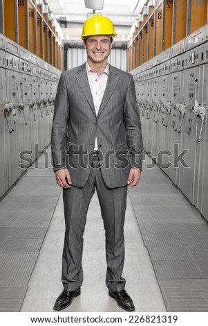 Full length portrait of smiling young male supervisor standing in control room