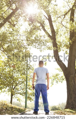 Full length rear view of fit man standing on path in park